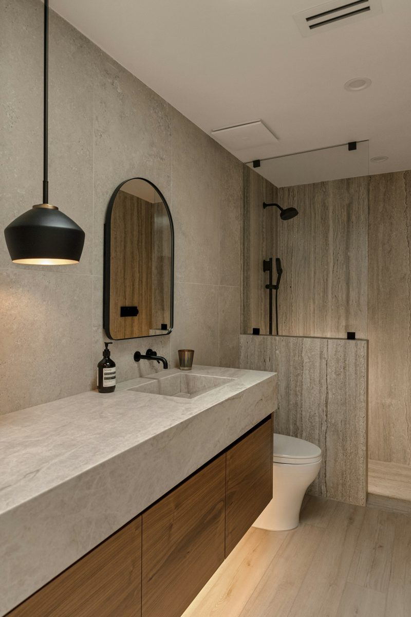 Baño moderno con mueble de madera, espejo y piedra natural